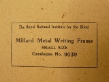Afbeelding van een metalen schrijfgeleider, Writingframe small; de verpakking met de naam van de leverancier: RNIB